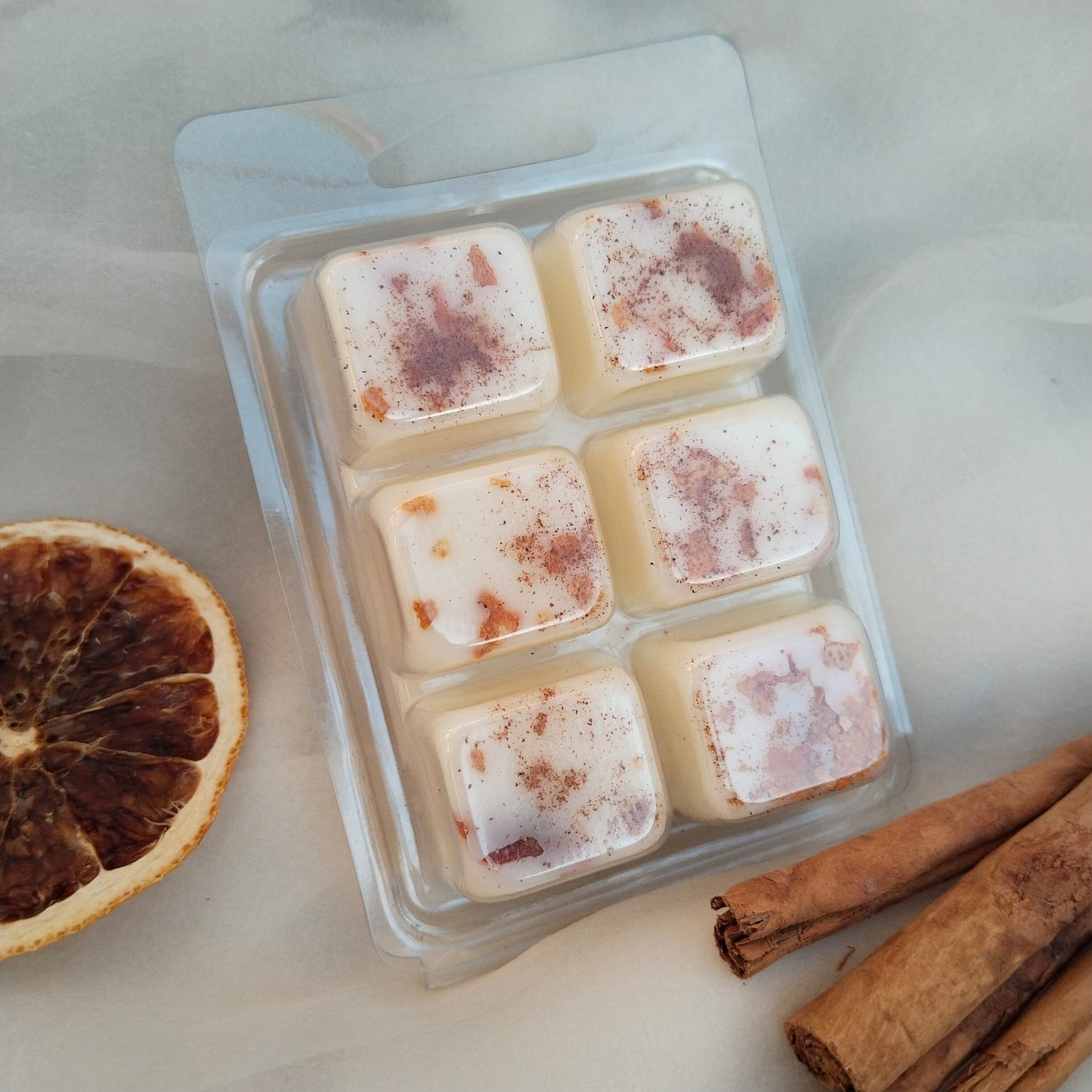 Clamshells de cera aromática de soja natural con fragancia de naranja y canela, aroma cítrico y especiado, ideal para crear momentos de bienestar en tu hogar. Producto artesano, sostenible y vegano.